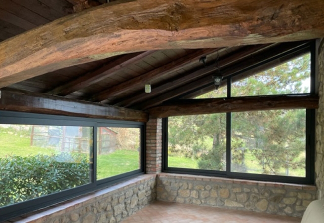 veranda in sasso con infissi in alluminio verniciato scuro