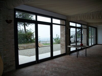 salone con vetrate scorrevoli con infissi in alluminio verniciato scuro e vista su giardino
