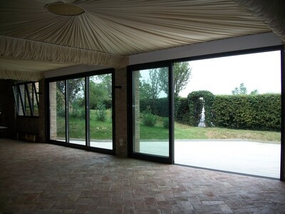 salone con vetrate scorrevoli con infissi in alluminio verniciato scuro e vista su giardino