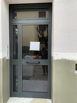 portone condominiale a vetri con infissi in alluminio verniciato scuro